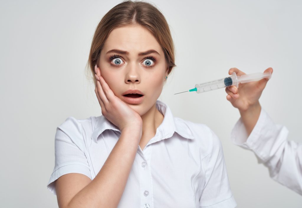 woman patient syringe in the hands of a doctor fear of injections phobia